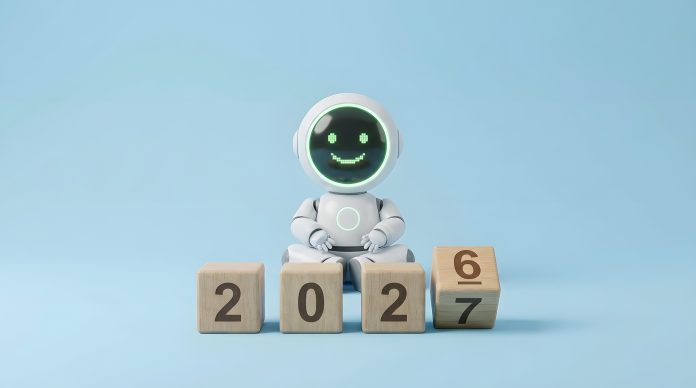 Small white AI robot sitting behind wooden toy blocks displaying the transition from year 2026 to 2027, representing future technology, new year concept, and artificial intelligence progress.